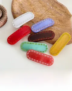 Dettaglio di fermagli colorati in acetato con strass su vassoio di marmo
