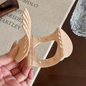 Vintage large matte beige shark hair claw clip for women in a lifestyle book setting