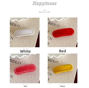 Dettaglio di quattro eleganti fermagli per capelli con strass in bianco, rosso, rosa e giallo