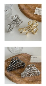Macro shot of gold and silver metal hair claws featuring pearl accents and skull hand designs