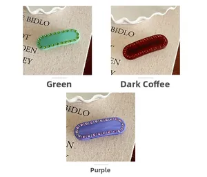 Dettaglio di fermagli per capelli in acetato verde, marrone e viola con bordo di strass