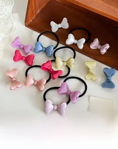 Détail des barrettes nœuds en résine pailletée et élastiques à cheveux en tons pastel