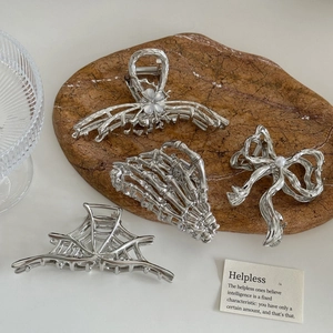 Silver alloy gothic butterfly and skull hair claws set on a brown marble tray