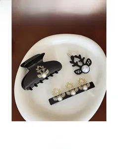 Macro shot of black acetate hair claw and reindeer hair pins with white pearls on a tray