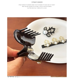 Detail of luxury deer-shaped acetate hair claw clips with pearls on a wooden surface