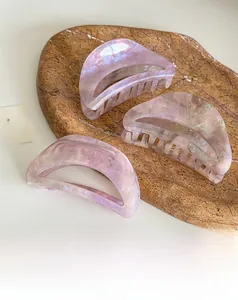 Dettaglio di fermagli per capelli in acetato viola perlato con texture geometrica