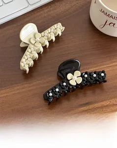 Detail of beige and black flower claw clips with pearls on a wooden desk setting