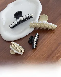 Close-up of elegant geometric pearl hair claws in black and beige on a ceramic plate