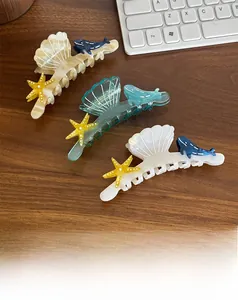 Macro detail of ocean-themed acetate hair claws with starfish and whale patterns