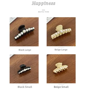 Detail showing large and small pearl hair claws in black and beige on wooden surface