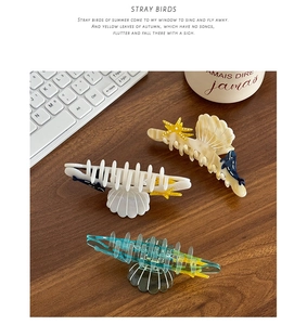 Detail of ocean-themed acetate hair claws featuring scallop, starfish, and whale designs