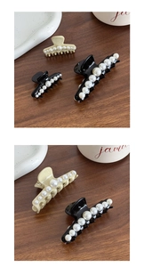 Detailed view of large French hair claws with white imitation pearls on a wooden desk