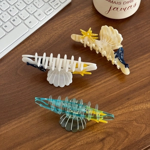 Marine theme acetate hair claws with shell starfish and whale designs on wooden desk