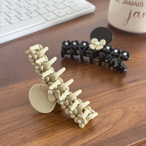 Elegant flower hair claw clips with pearls on a wooden desk with a coffee cup