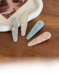 Detailed view of four geometric acetate hair clips with crystal accents and textured finish