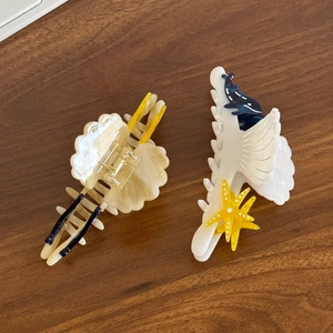 Marine series acetate hair clips with dolphin and starfish designs on wooden background