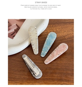 Close-up of four wavy acetate hair clips with small rhinestones on wooden background