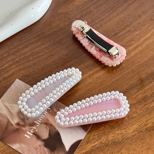 Three-piece acetate hair clip set with pearls and marble pattern on wooden surface