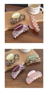 Detail of luxury acetate shark hair clips with marble patterns on a wooden tray