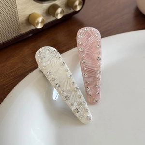 Elegant shell texture hair clips with crystals in cream and pink on a white plate