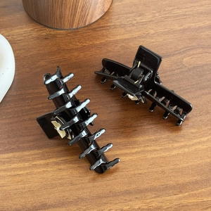 Pinces à cheveux noires élégantes avec motif de fleurs 3D sur un fond de bois brun