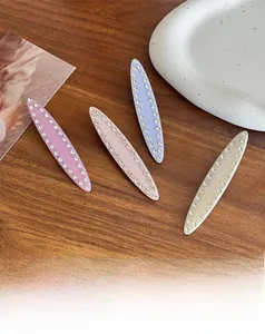 Gros plan de quatre barrettes de luxe en strass aux couleurs pastel sur du bois