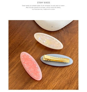 Close-up of three marble resin hair clips with rhinestones on a wooden background