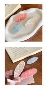 Close-up of three acetate hair clips in pastel pink, cream, and blue with small rhinestones