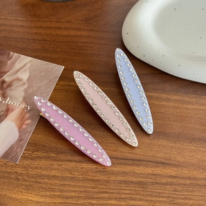 Trois pinces à cheveux en acétate violet, rose et bleu avec strass sur bois foncé