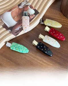 Detailed close-up of colorful acetate hair clips with inlaid rhinestones and marble texture