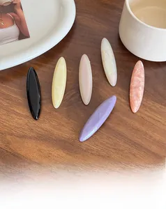 Set of 6 colorful acetate hair clips in geometric shapes displayed on a wooden surface