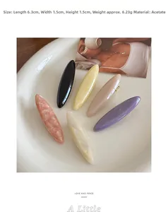 Detail view of acetate hair clips in various colors on a ceramic tray, 6.3cm length