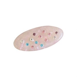 Pastel pink oval acetate hair clip with colorful rhinestones on a white background