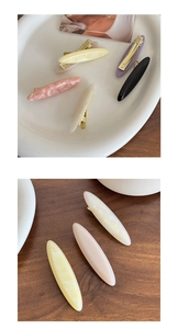 Detailed close-up of marble pattern acetate duckbill hair clips with gold metal springs