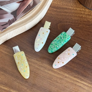 Elegant four-piece acetate hair clip set with colorful rhinestones on wood background