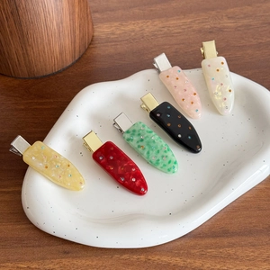 Set of 6 marble textured acetate hair clips with rhinestones on a ceramic tray
