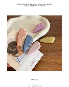 Detail view of five glittery acetate teardrop hair clips in candy colors on a ceramic tray