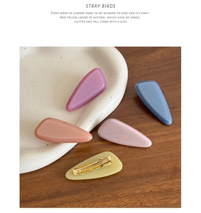 Detailed view of five glitter candy-colored acetate hair clips on a ceramic plate