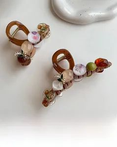 Macro detail of amber resin hair claw clips with beads and lily of the valley floral accents