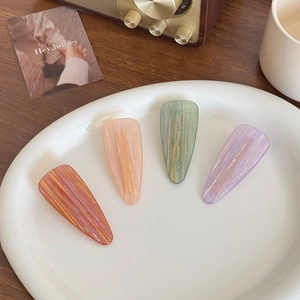 Set of four colorful water drop hair clips with glitter stripes on a white ceramic tray