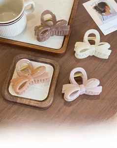 Detail showing four jelly-colored bow hair claws in brown, beige, and pink shades