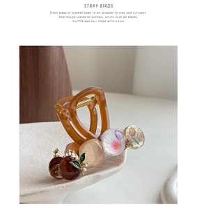 Detail of vintage hair claw clip featuring amber resin, dried flower beads and tulips