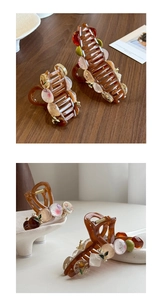 Detailed view of amber claw clip with painted beads and pearls on wooden surface