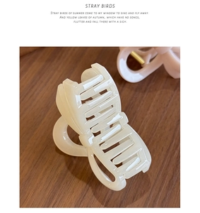 Detail of cream white and pink 3D bow hair claws with glossy resin finish on wood
