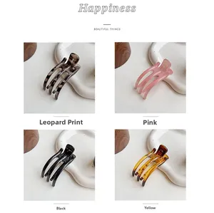 Close-up of four colored resin hair clips in leopard, pink, black and amber yellow