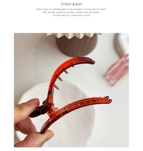Detail of amber translucent hair claw clip with multi-tooth curved design for daily styling