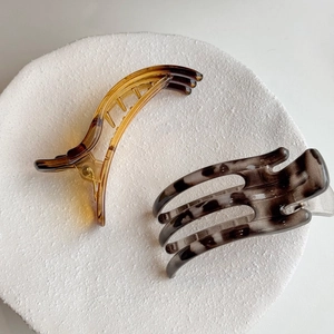Minimalist jelly amber and tortoiseshell claw hair clips on a white display plate