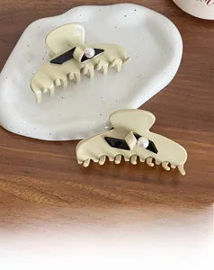 Detail of cream resin hair claws with black accents and pearls on a ceramic tray