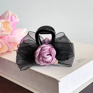 Détail d'une pince à cheveux à nœud en résille noire avec une rose en tissu violet