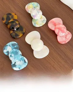 Gros plan de cinq pinces à cheveux fleuries en acétate sur une table en bois foncé